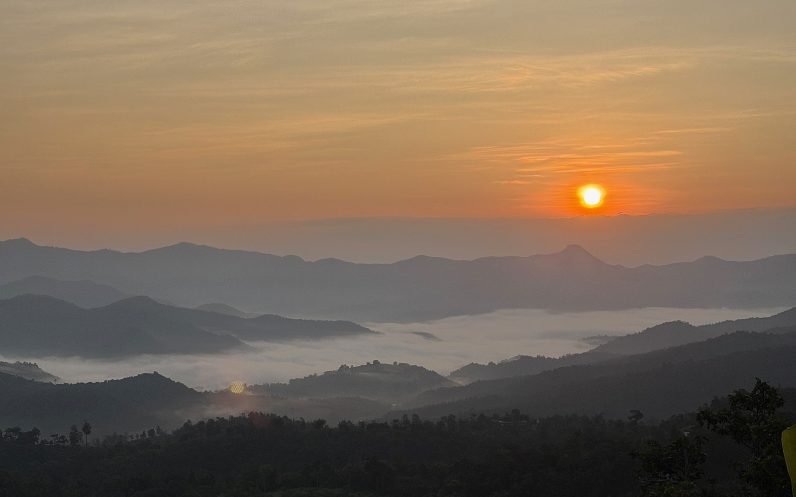 Sun rising over layered mountains and mist in the valley