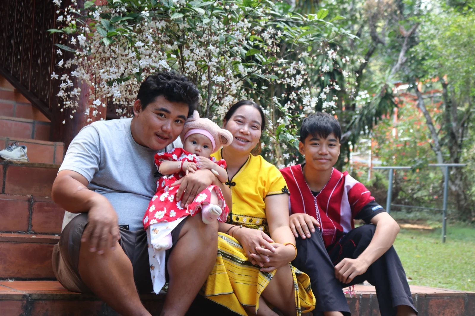 Your guide with his wife, son and baby daughter on the steps of their home, under a flowering tree