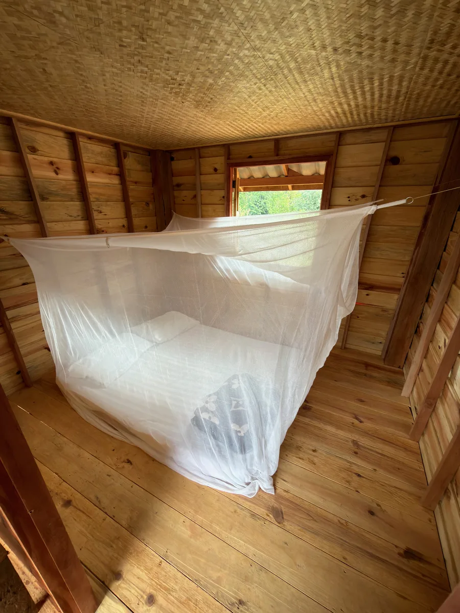 Private wooden room with a single netted bed